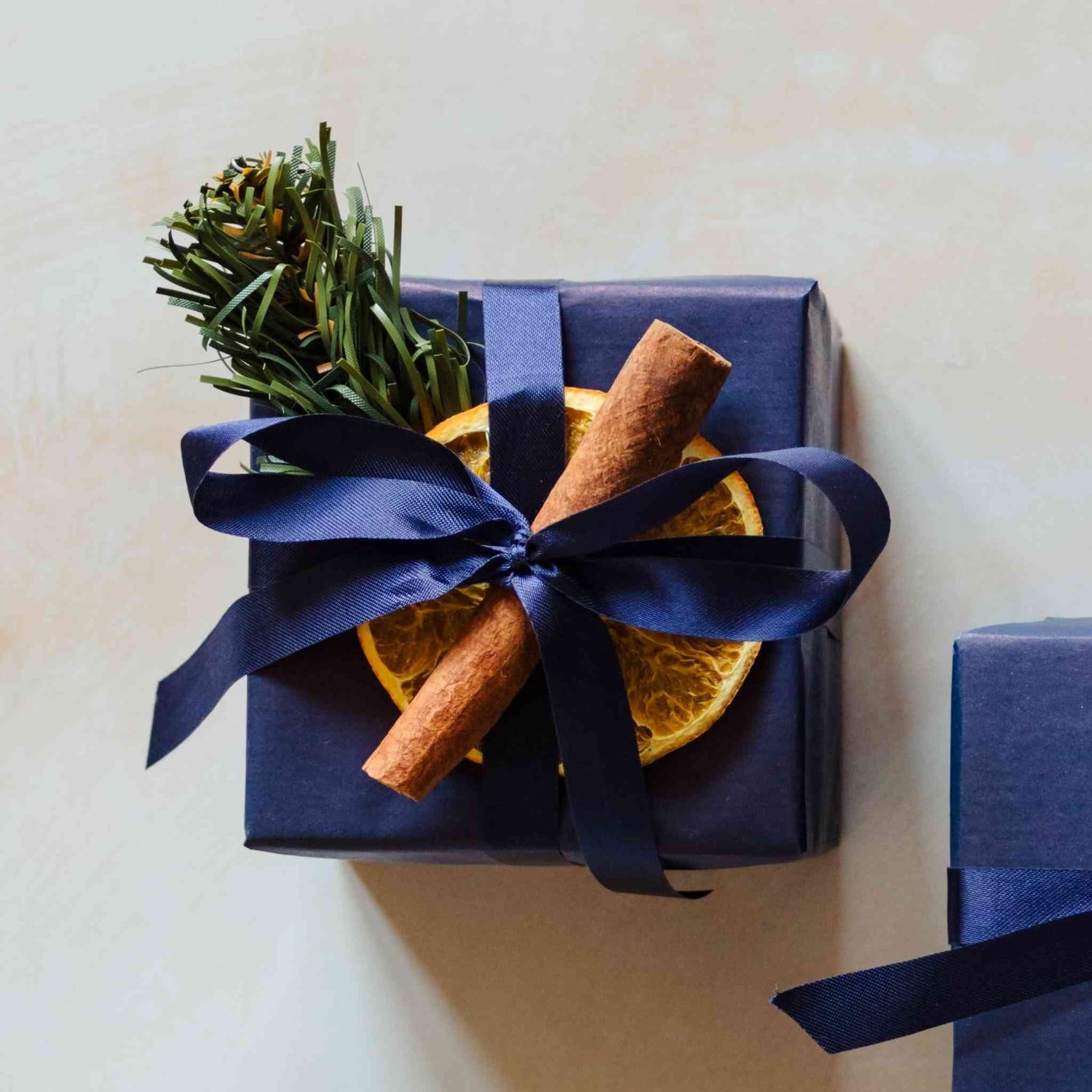 A 200g linen scented soy candle from the Home County Co. is shown with luxury Christmas Gift Wrap. The candle is wrapped in luxury navy wrapping paper secured with navy ribbon and Christmas embellishments.