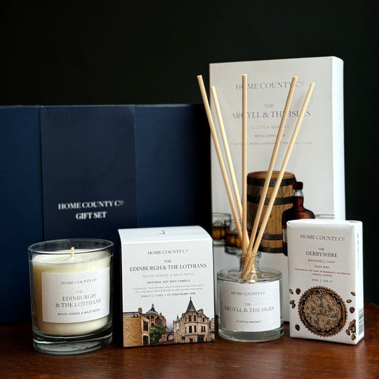 Home County Co. County Collection Gift Set shows an Edinburgh candle, argyll reed diffuser and deryshire soap bar in front of the luxury navy gift set box