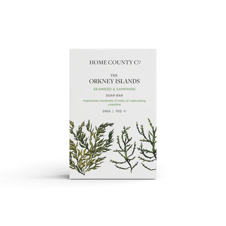 A seaweed and samphire scented natural soap bar from the Home County Co. is shown in its seaweed illustrated recyclable soap bar wrap