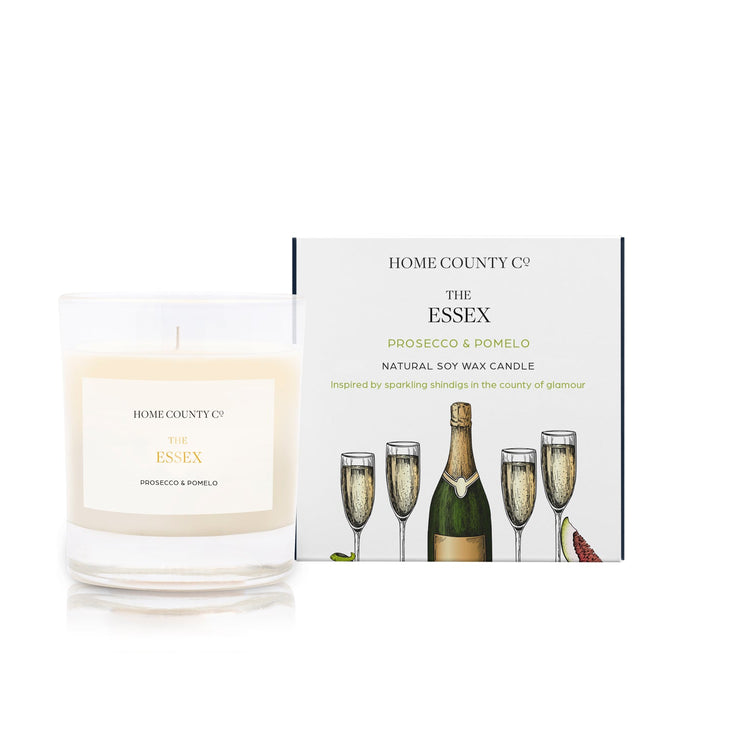 A prosecco and pomelo scented soy wax candle inspired by Essex is shown next to its sustainable candle box with prosecco bottle illustration