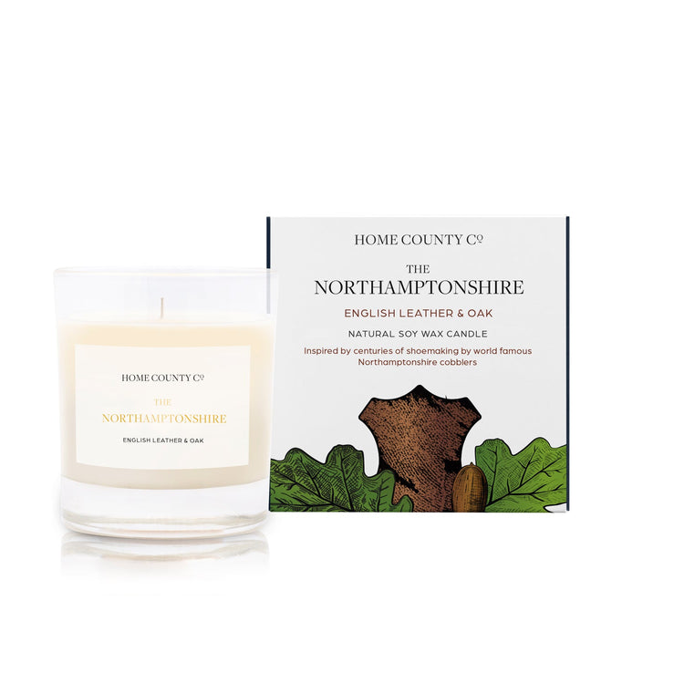 An English leather and oak scented soy wax candle inspired by Northamptonshire is shown next to its sustainable candle box with leather illustration