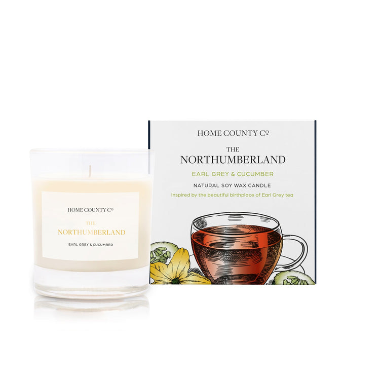 An earl grey and cucumber scented soy wax candle inspired by Northumberland is shown next to its sustainable candle box with teacup illustration