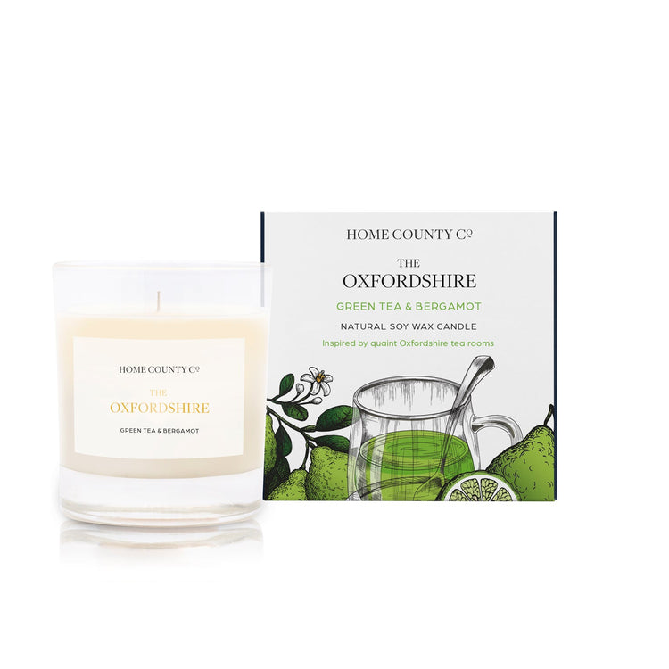 A green tea and bergamot scented soy wax candle inspired by Oxfordshire is shown next to its sustainable candle box with green tea illustration