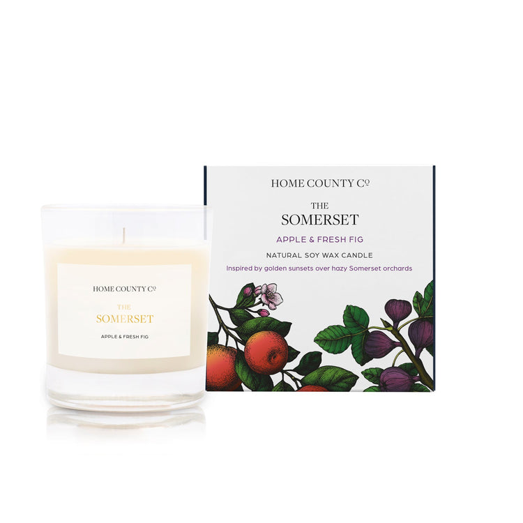 An apple and fresh fig scented soy wax candle inspired by Somerset is shown next to its sustainable candle box with apple and fig illustration