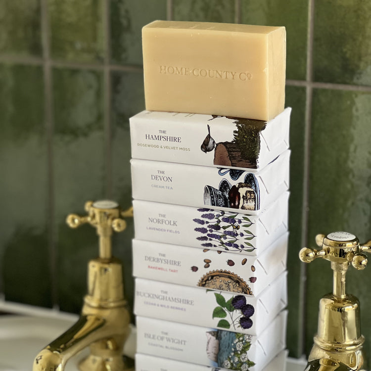 A stack of Home County Co. county soap bars is shown on a bathroom sink
