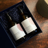 The Meadows Peony and Wildflowers liquid hand soap and lotion gift set is shown with the amber bottles in an open gift set box on a table.