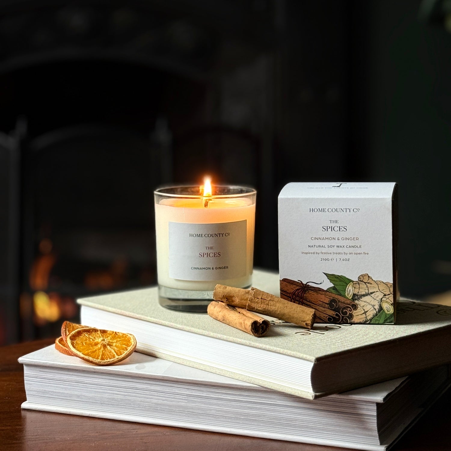Candle with packaging on books in front of a fireplace