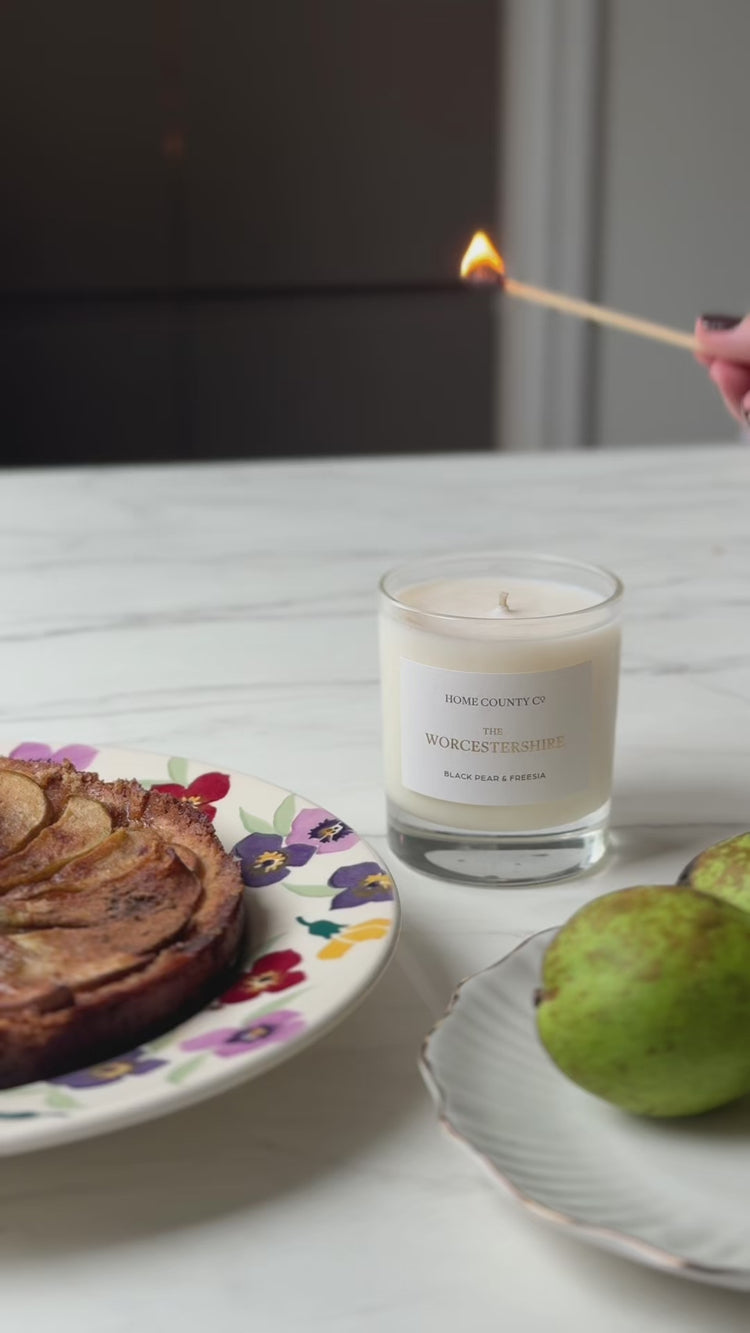 The Worcestershire pear and freesia candle is lit with a pear tart and pears in the foreground