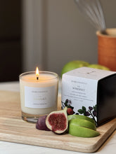 Somerset candle by Home County Co. is lit and shown next to its candle box with apple crumble in foreground