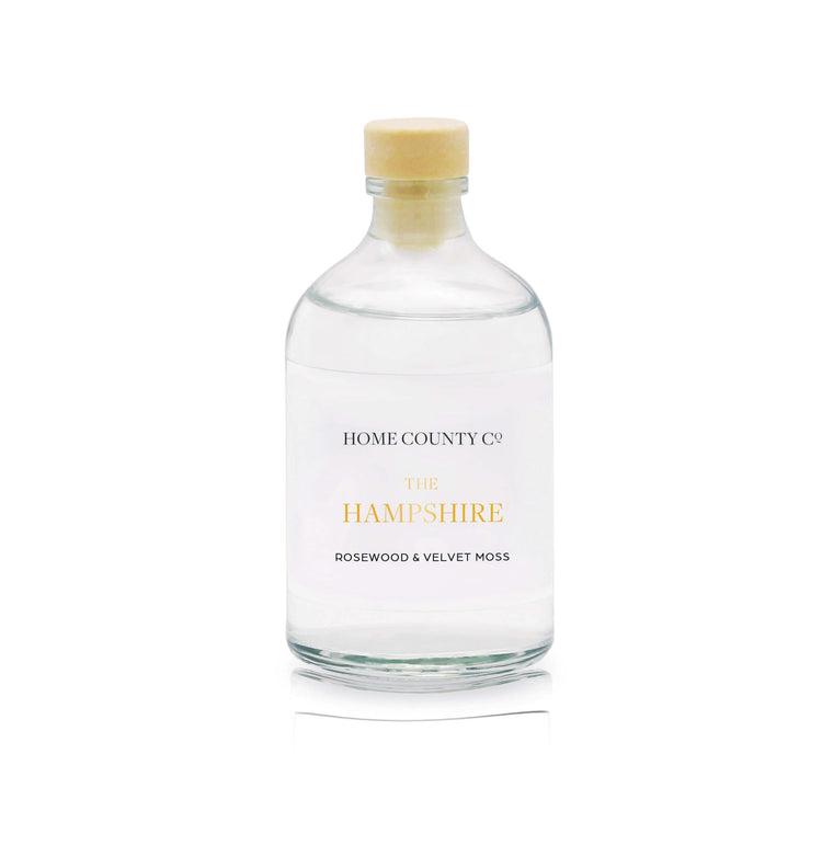 A rosewood and velvet moss reed diffuser refill is shown in a recyclable glass bottle