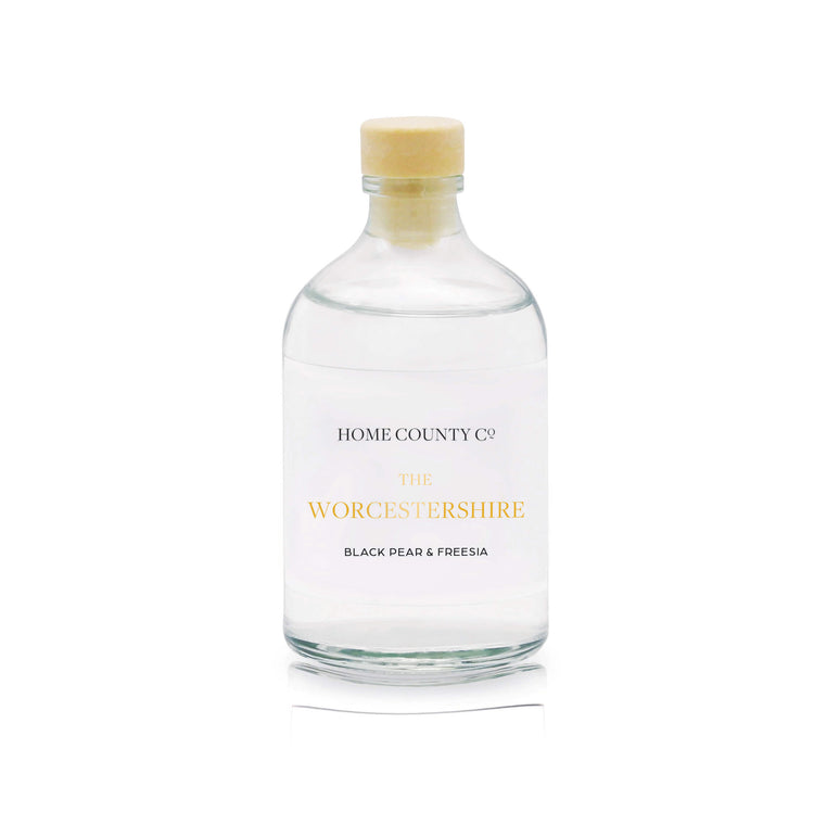 A black pear and freesia scented reed diffuser refill from Home County Co. The eco friendly reed diffuser refill is shown in its recyclable glass bottle.