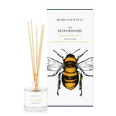 A honey and nectar fruits scented reed diffuser from Home County Co. The vegan friendly reed diffuser is shown next to the eco friendly reed diffuser box packaging.