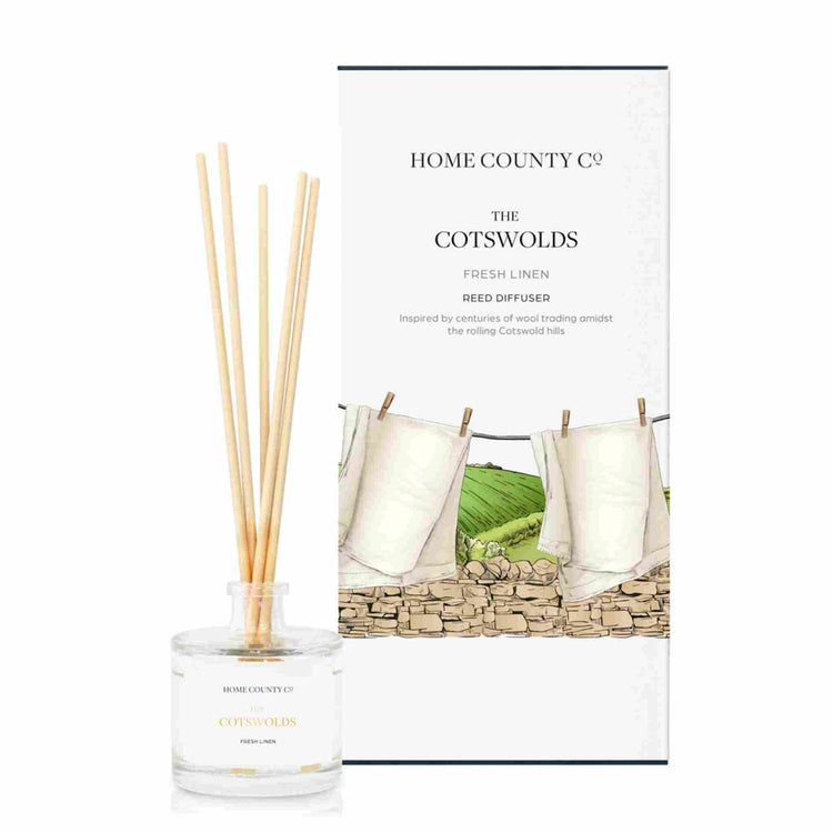 A fresh linen scented reed diffuser from Home County Co. The vegan friendly reed diffuser is shown next to the eco friendly reed diffuser box packaging.
