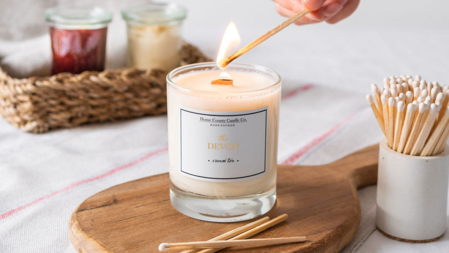 The Devon Cream Tea scented candle from Home County Co is shown being lit with a long match