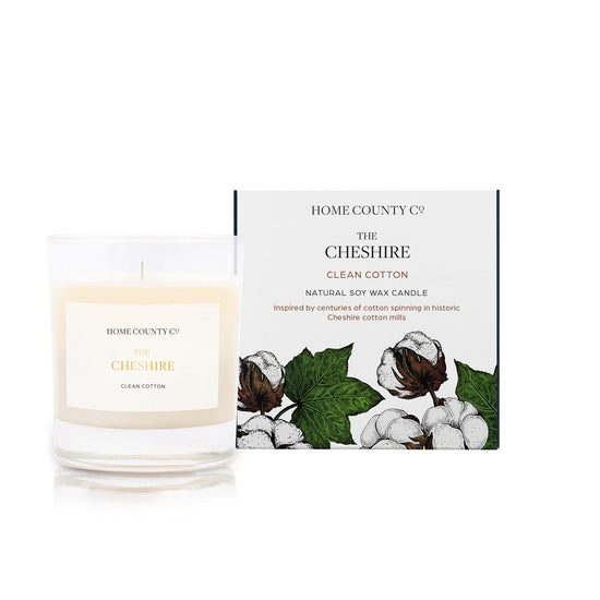 A clean cotton scented soy wax candle inspired by Cheshire is shown next to its sustainable candle box with cotton illustration