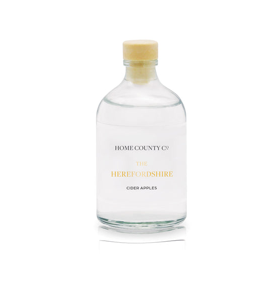 A cider apple scented reed diffuser refill from the Home County Co is shown in its recyclable glass refill bottle.