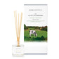 A freshly cut grass scented reed diffuser from Home County Co. The vegan friendly reed diffuser is shown next to the eco friendly reed diffuser box packaging with Cotswold hills illustration.
