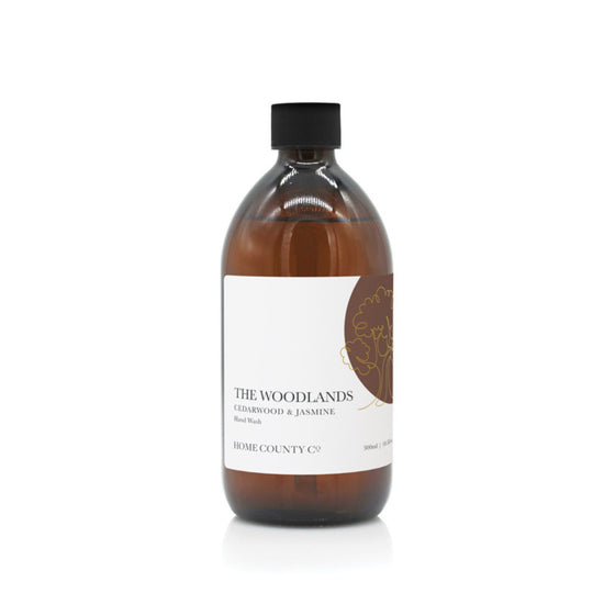 A 500ml woody, masculine hand wash refill from the Home County Co. is shown in its recyclable amber glass hand wash bottle with recyclable hand wash refill cap.