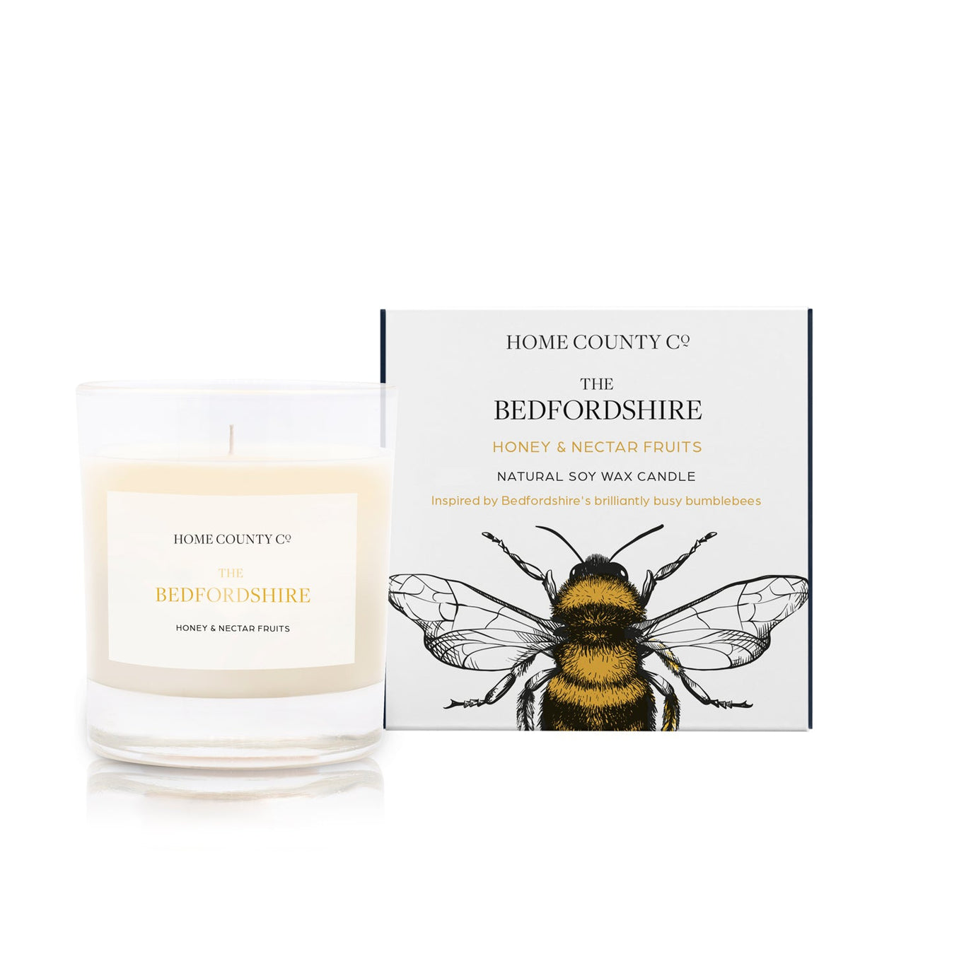 A honey and nectar fruits scented soy wax candle inspired by Bedfordshire is shown next to its sustainable candle box with honeybee illustration