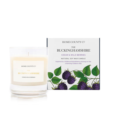 A blackberry and bay scented soy wax candle inspired by Buckinghamshire is shown next to its sustainable candle box with blackberry illustration