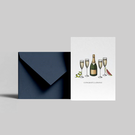 A champagne bottle illustrated congratulations greeting card with congratulations message from the Home County Co. is shown with its navy envelope.