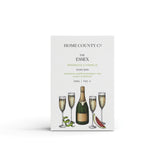 A prosecco scented natural soap bar from the Home County Co. is shown in its prosecco illustrated recyclable soap bar wrap