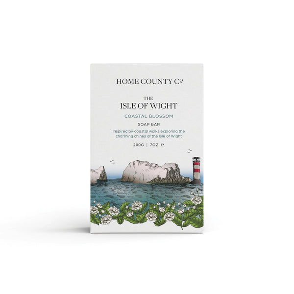 A coastal blossom scented natural soap bar from the Home County Co. is shown in its Isle of Wight needles illustrated recyclable soap bar wrap