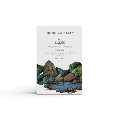 A freshwater minerals scented natural soap bar from the Home County Co. is shown in its Lake District illustrated recyclable soap bar wrap