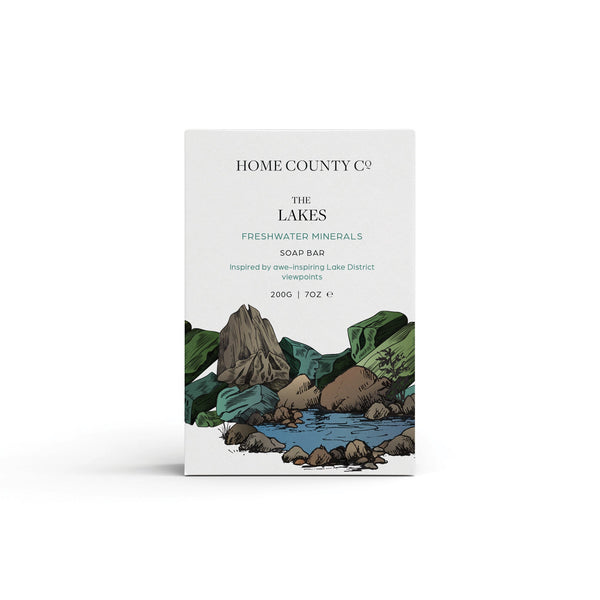 A freshwater minerals scented natural soap bar from the Home County Co. is shown in its Lake District illustrated recyclable soap bar wrap