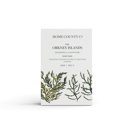 A seaweed and samphire scented natural soap bar from the Home County Co. is shown in its seaweed illustrated recyclable soap bar wrap