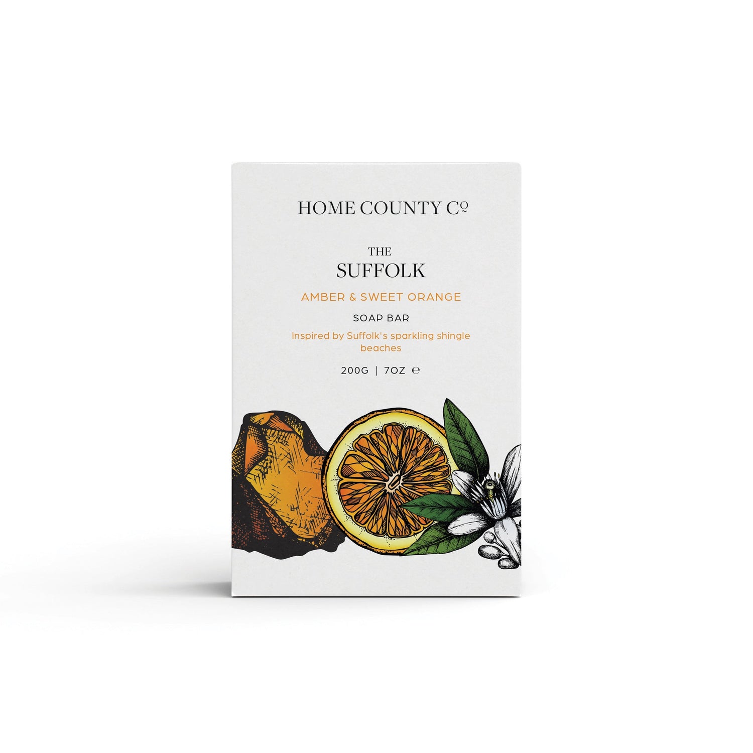 An amber and sweet orange scented natural soap bar from the Home County Co. is shown in its orange illustrated recyclable soap bar wrap