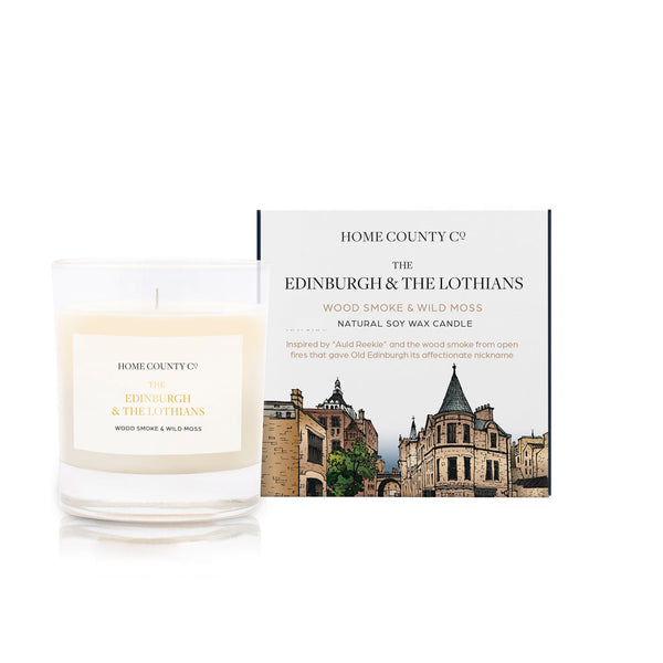 A wood smoke and wild moss scented soy wax candle inspired by Edinburgh and the Lothians is shown next to its sustainable candle box with Edinburgh Royal Mile illustration