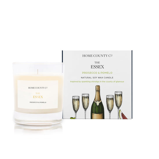 A prosecco and pomelo scented soy wax candle inspired by Essex is shown next to its sustainable candle box with prosecco bottle illustration