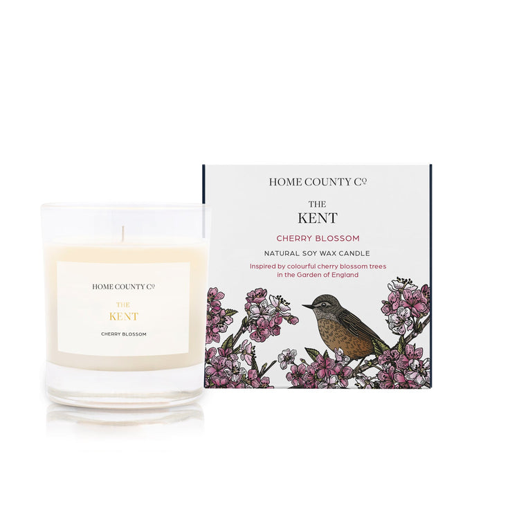 A Cherry Blossom scented soy wax candle inspired by Kent is shown next to its sustainable candle box with Cherry Blossom illustration