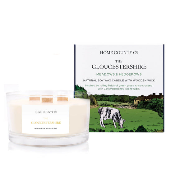 A freshly cut grass scented 3 wick candle from the Home County Co. is shown next to its eco-friendly candle packaging box.