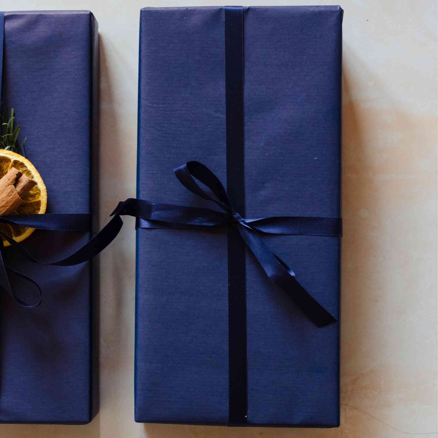 A wood smoke scented reed diffuser from the Home County Co. is shown with luxury Gift Wrap. The reed diffuser is wrapped in luxury navy wrapping paper secured with navy ribbon.