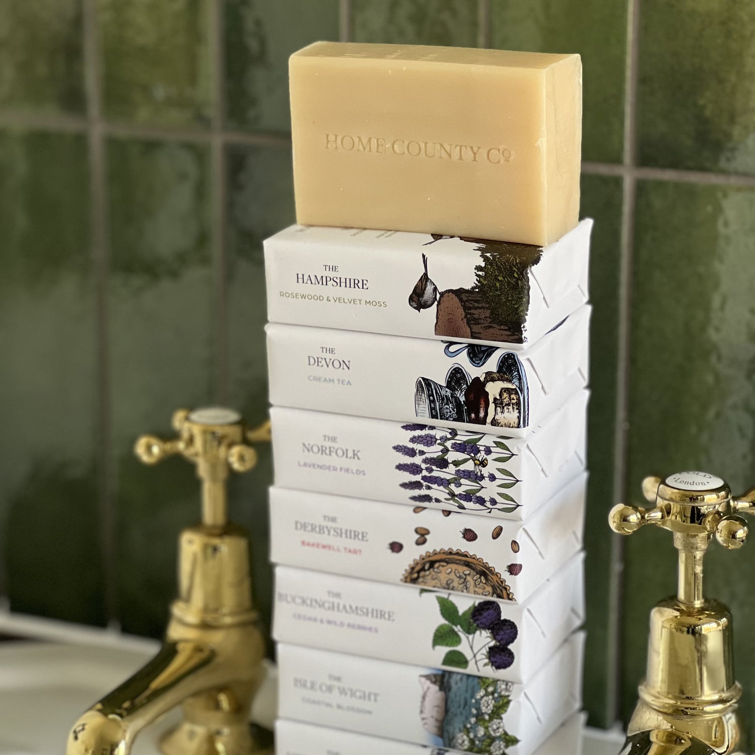A stack of Home County Co. county soap bars is shown on a bathroom sink