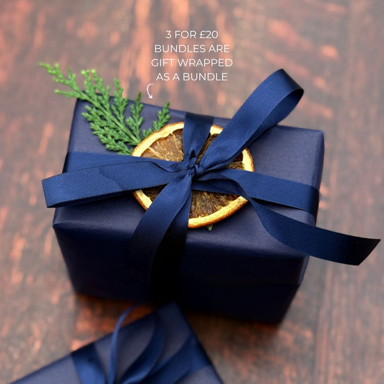 A Home County Co. soap bar bundle is shown with Christmas gift wrap - navy wrapping paper with navy ribbon and a dried orange slice and Christmas foliage
