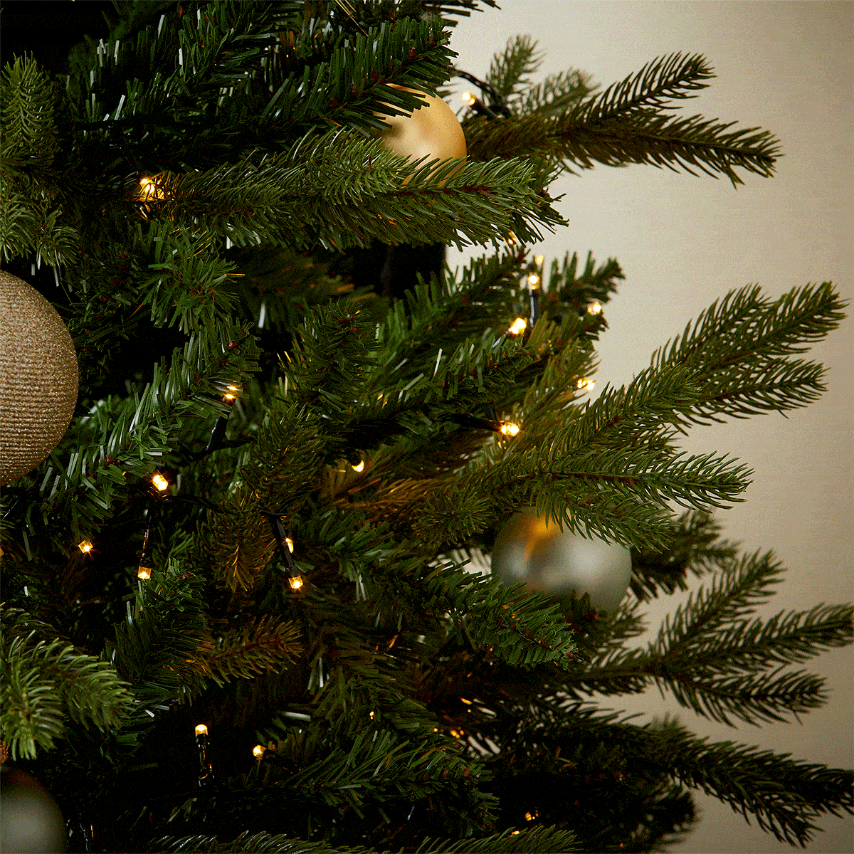 A cinnamon and ginger votive Christmas candle from the Home County Co. is shown in eco-friendly packaging being hung on the Christmas tree