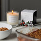 Candle with a lit flame next to a box labeled &