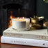 The Cinnamon and Ginger scented 3 wick candle from the Home County Co. is shown alight with a roaring log fire in the background