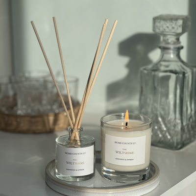 Candle and diffuser set on a surface with a blurred background