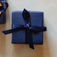 A 200g soy candle from the Home County Co. is shown with luxury Gift Wrap. The candle is wrapped in luxury navy wrapping paper secured with navy ribbon.