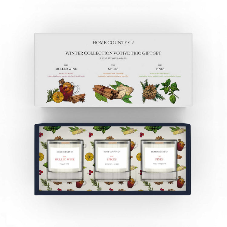 A Christmas candle gift set from the Home County Co. 3 votive soy candles are shown inside their eco-friendly box packaging.