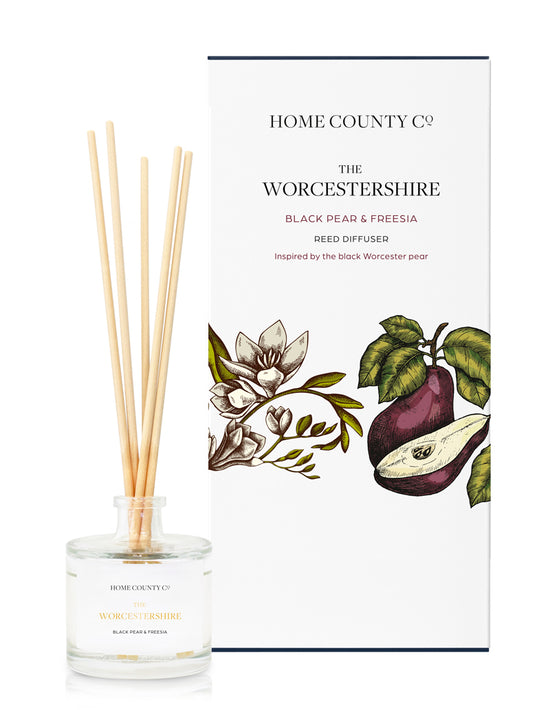 A black pear and freesia scented reed diffuser from Home County Co. The vegan friendly reed diffuser is shown next to the eco friendly reed diffuser box packaging.