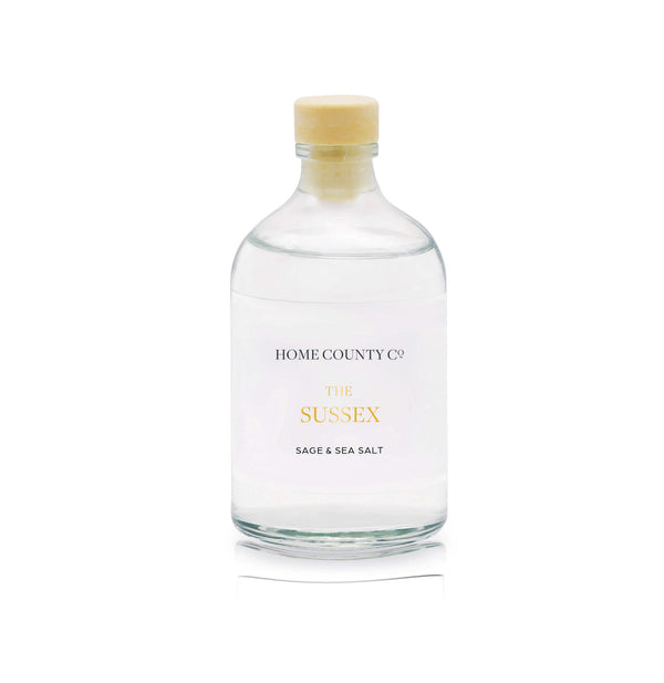 A sage and sea salt reed diffuser refill is shown in a recyclable glass bottle