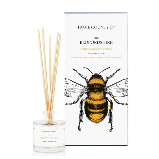 A honey and nectar fruits scented reed diffuser from Home County Co. The vegan friendly reed diffuser is shown next to the eco friendly reed diffuser box packaging.