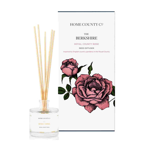A royal county rose scented reed diffuser from Home County Co. The vegan friendly reed diffuser is shown next to the eco friendly reed diffuser box packaging.