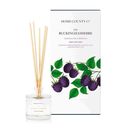 A cedar and wild berries scented reed diffuser from Home County Co. The vegan friendly reed diffuser is shown next to the eco friendly reed diffuser box packaging.