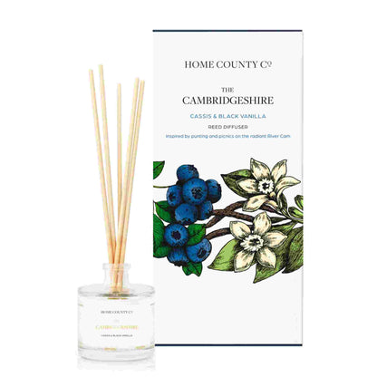 A cassis and black vanilla scented reed diffuser from Home County Co. The vegan friendly reed diffuser is shown next to the eco friendly reed diffuser box packaging.